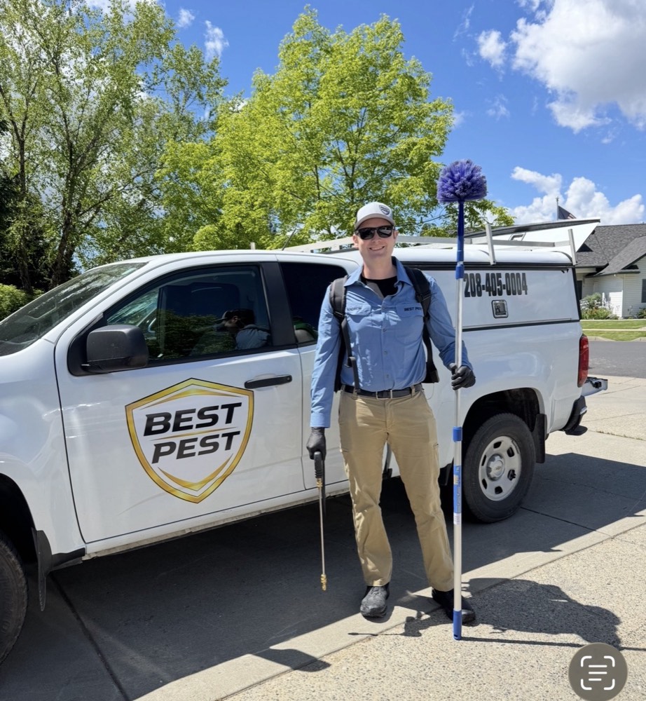 Andrew, owner of Best Pest, with cobweb brush and sprayer in front of his branded Best Pest truck in Coeur d'Alene, Idaho